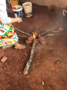 woman using branches to light a fire to cook with