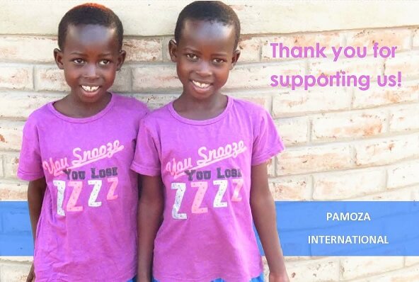 Two children standing against a wall wearing Pamoza international t-shirts