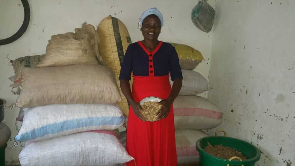 Bester Gondwe posing for an indoor photo as she smiles and stands by bags of rice