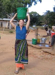 Melissa carrying water on her head after getting it from the borehole